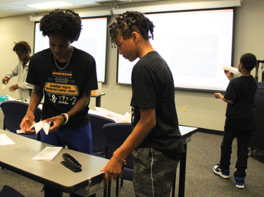 two male students building paper airplane